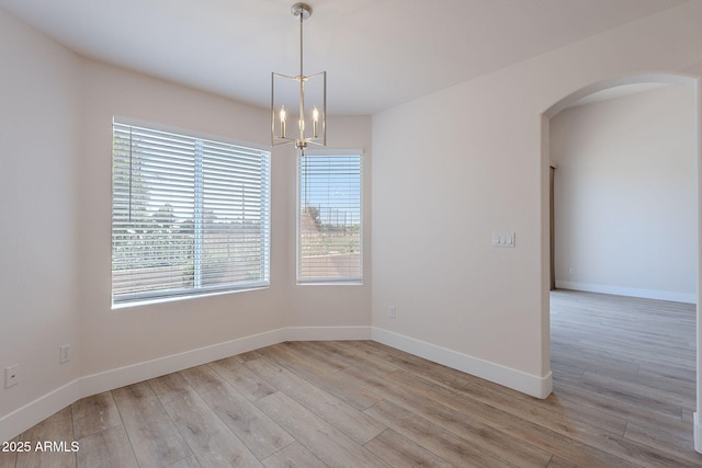 2647 N Miller Rd Unit 6, Scottsdale, AZ 85257 - spare room featuring light wood-style flooring, arched walkways, and a chandelier