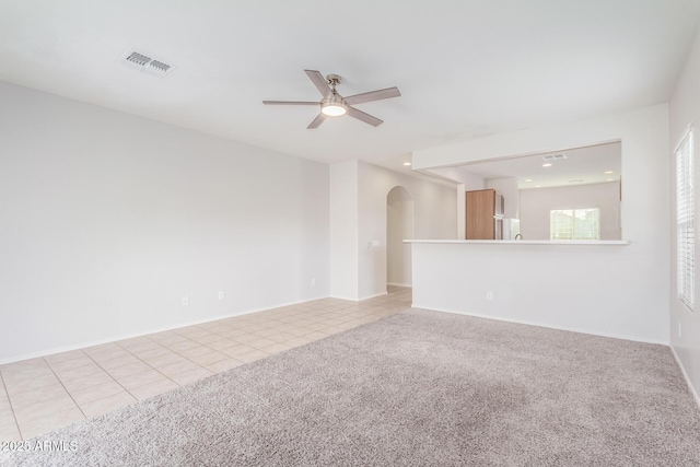 5590 W Victory Way, Florence, AZ 85132 - spare room featuring arched walkways, a ceiling fan, light tile patterned flooring, light colored carpet, and baseboards