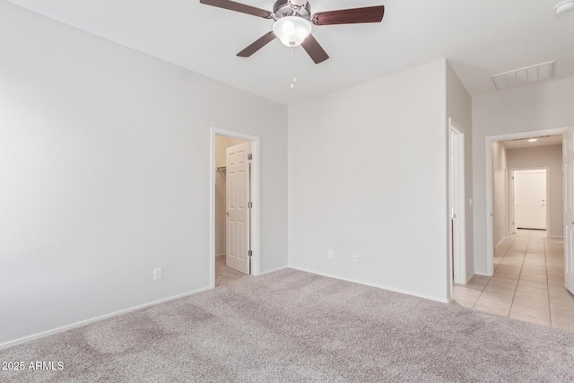 5590 W Victory Way, Florence, AZ 85132 - unfurnished bedroom featuring light carpet, baseboards, a walk in closet, a ceiling fan, and light tile patterned flooring