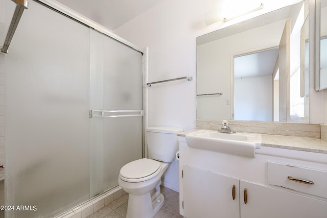 bathroom featuring a shower with door, vanity, toilet, and tile patterned floors