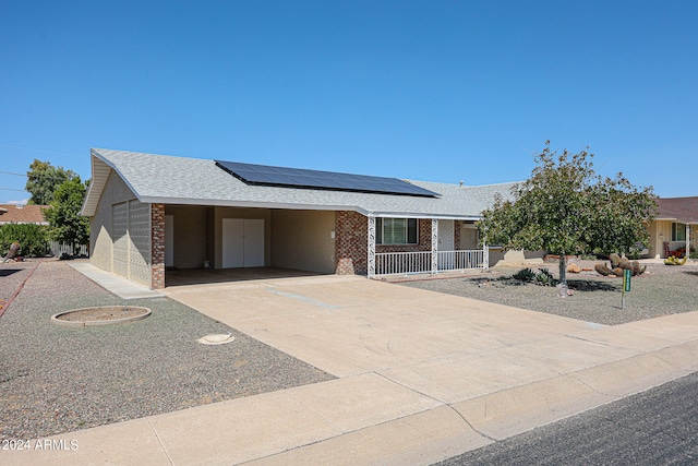 single story home with a garage, covered porch, and solar panels