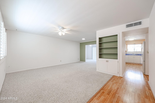 unfurnished living room with light wood-type flooring and ceiling fan