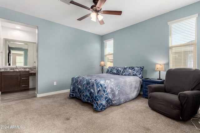 carpeted bedroom with ensuite bathroom, ceiling fan, and sink