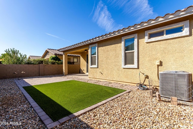 rear view of house with central AC unit, a patio, and a lawn