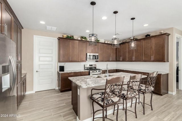 kitchen with dark brown cabinets, stainless steel appliances, light stone counters, and hanging light fixtures