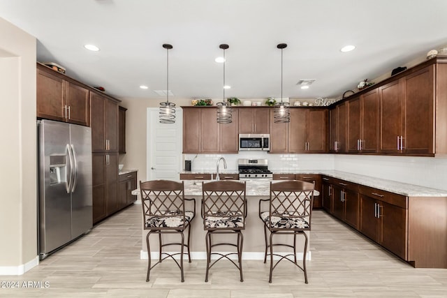 kitchen with pendant lighting, dark brown cabinets, a center island with sink, and stainless steel appliances