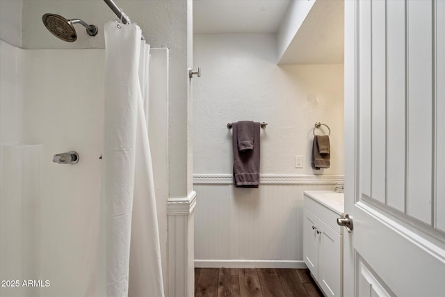 3551 N 12th St Unit 101, Phoenix, AZ 85014 - full bath featuring vanity, wood finished floors, wainscoting, and a shower with shower curtain