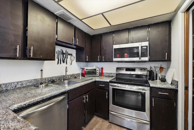 3551 N 12th St Unit 101, Phoenix, AZ 85014 - kitchen featuring appliances with stainless steel finishes, light wood-style flooring, and dark brown cabinetry
