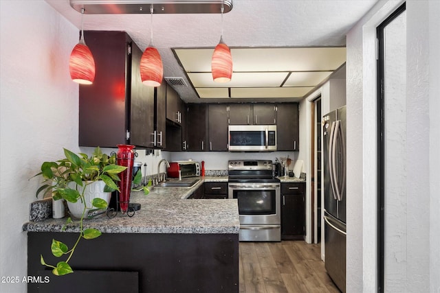 3551 N 12th St Unit 101, Phoenix, AZ 85014 - kitchen featuring stainless steel appliances, light wood-type flooring, light countertops, and pendant lighting