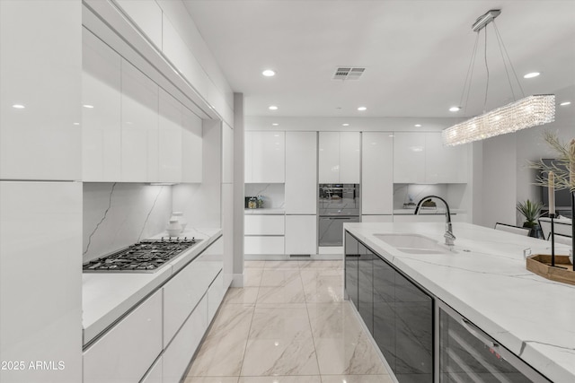 kitchen featuring white cabinetry, stainless steel gas cooktop, pendant lighting, light stone counters, and sink