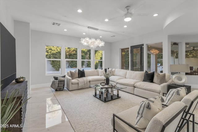 living room with ceiling fan with notable chandelier