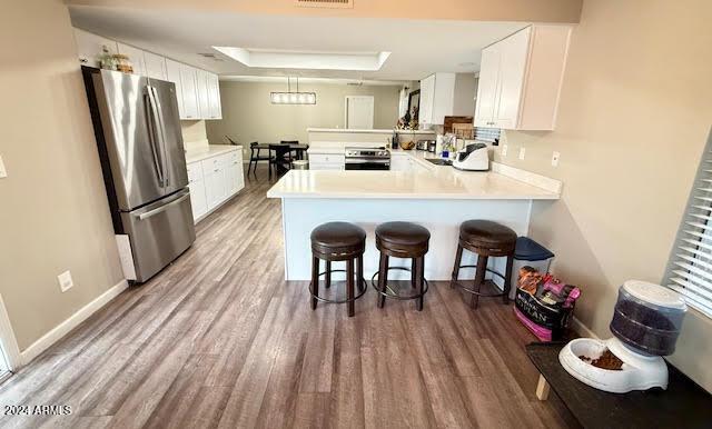 kitchen featuring kitchen peninsula, appliances with stainless steel finishes, and white cabinetry