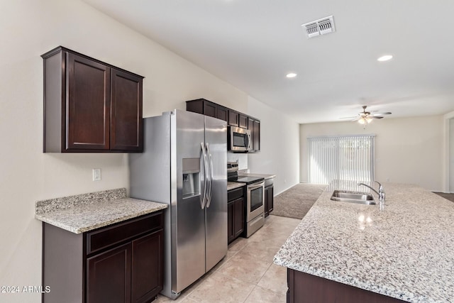 kitchen featuring light stone countertops, sink, appliances with stainless steel finishes, ceiling fan, and dark brown cabinetry