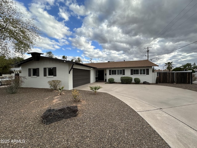 ranch-style house featuring concrete driveway, an attached garage, and fence