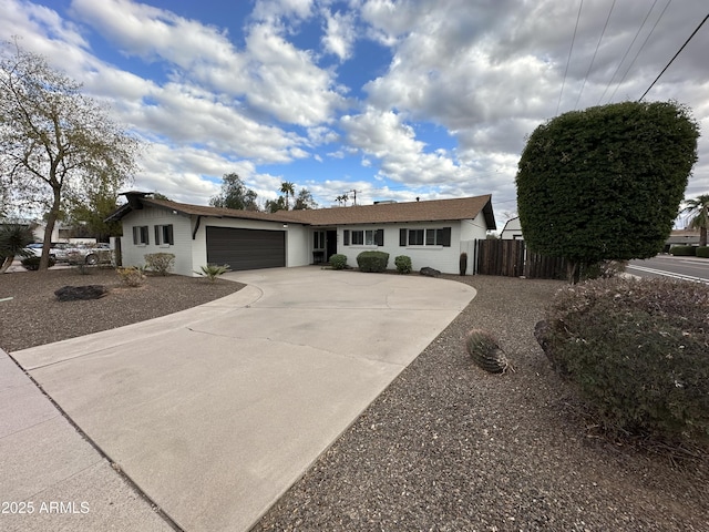 ranch-style house with concrete driveway, fence, and a garage