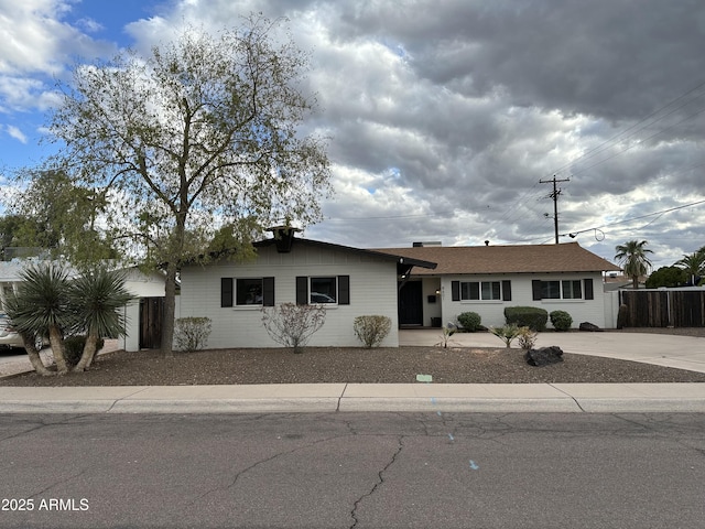 ranch-style home with concrete driveway and fence