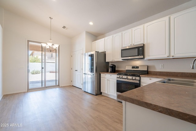1956 N Hubbard Ln, Casa Grande, AZ 85122 - kitchen with dark countertops, a sink, a chandelier, stainless steel appliances, and light wood-type flooring