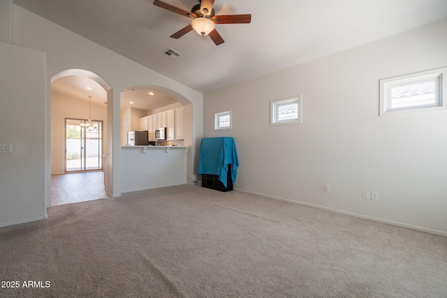 1956 N Hubbard Ln, Casa Grande, AZ 85122 - unfurnished living room featuring light colored carpet, visible vents, arched walkways, ceiling fan with notable chandelier, and vaulted ceiling