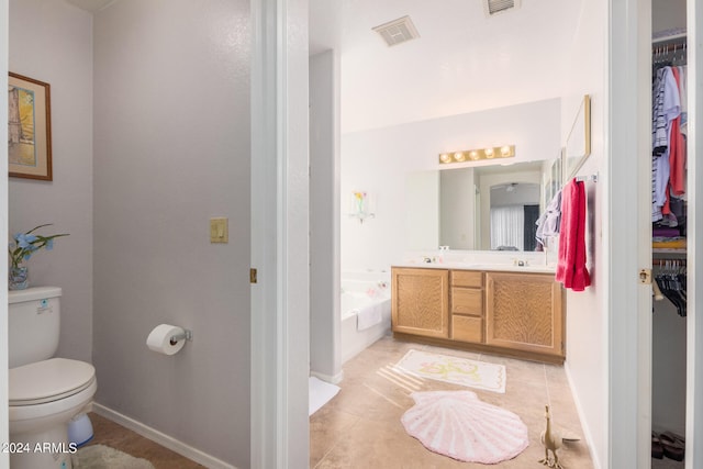 bathroom featuring tile patterned flooring, a tub, vanity, and toilet