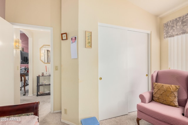 sitting room with vaulted ceiling and light colored carpet