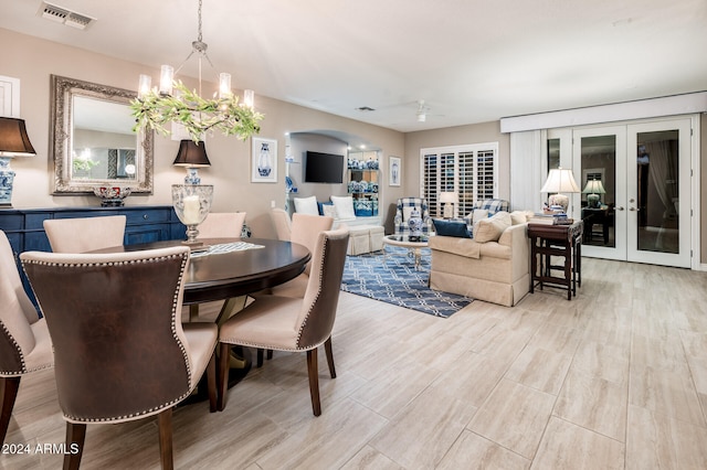 dining space with light hardwood / wood-style flooring, french doors, and a chandelier