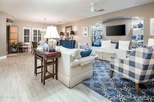 living room with light wood-type flooring and ceiling fan with notable chandelier