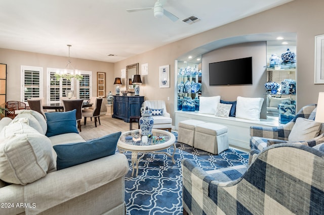 living room with hardwood / wood-style floors and ceiling fan with notable chandelier