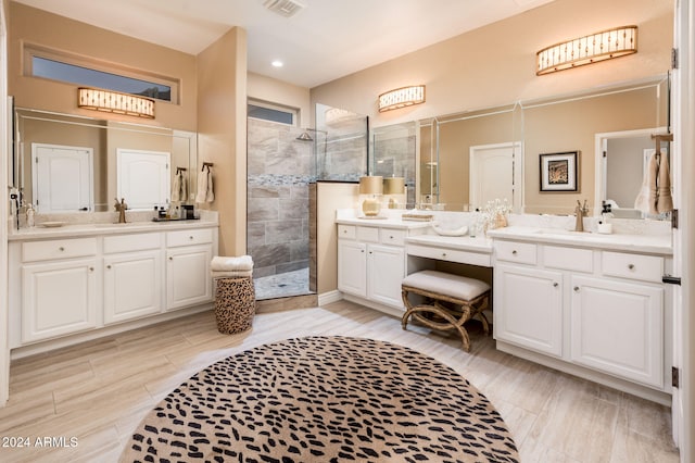 bathroom with a tile shower and vanity