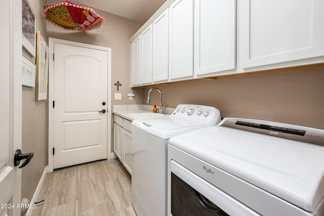 clothes washing area with sink, independent washer and dryer, and cabinets