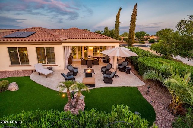 back house at dusk featuring a patio and a yard