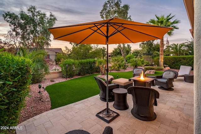 patio terrace at dusk with an outdoor fire pit and a lawn