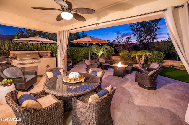 patio terrace at dusk with an outdoor living space, exterior kitchen, grilling area, and ceiling fan