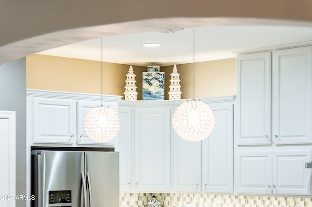 interior details featuring white cabinetry, stainless steel refrigerator with ice dispenser, decorative light fixtures, and backsplash