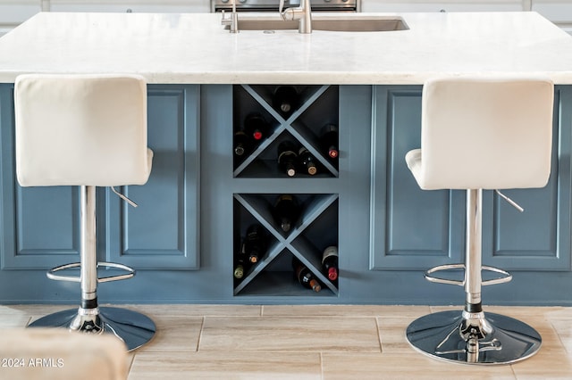 bar with light stone countertops, blue cabinets, and hardwood / wood-style floors