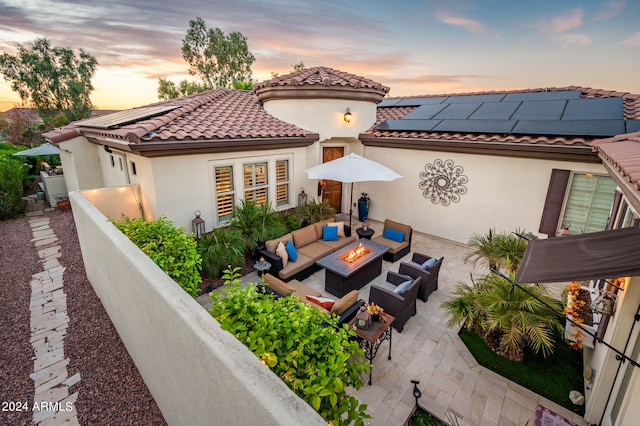 back house at dusk featuring a patio area, an outdoor hangout area, and solar panels