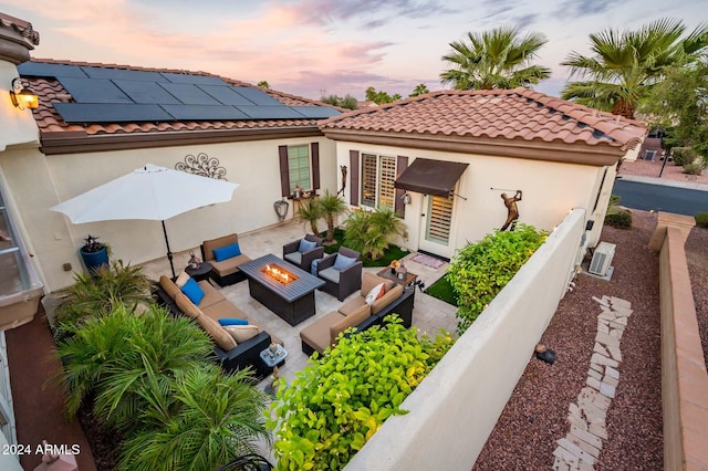 back house at dusk featuring an outdoor hangout area, solar panels, and a patio