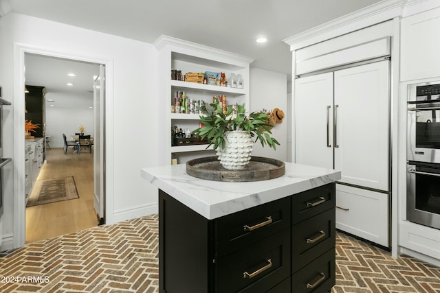 kitchen with white cabinetry, a kitchen island, paneled fridge, and stainless steel double oven