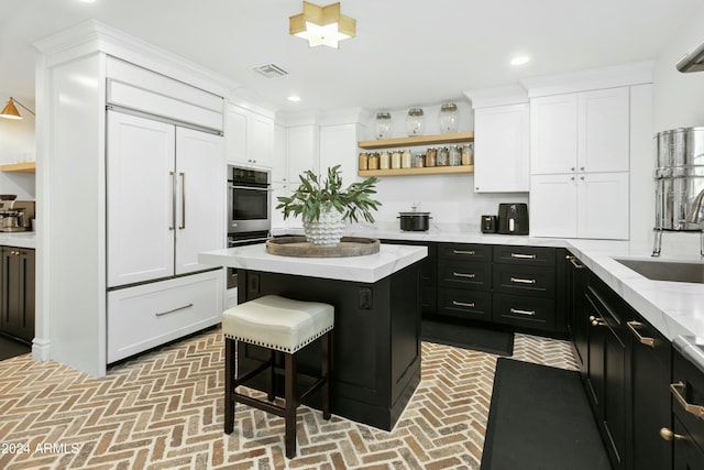 kitchen with white cabinetry, a kitchen island, sink, and a breakfast bar