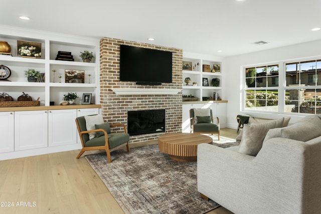 living room with a brick fireplace and light hardwood / wood-style flooring