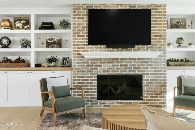 sitting room with wood-type flooring and a brick fireplace