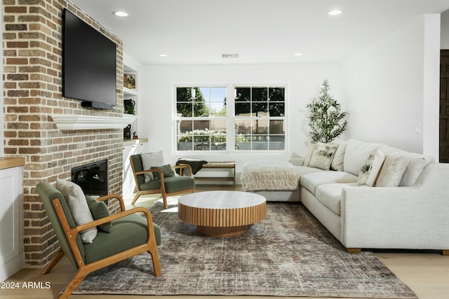 living room featuring a brick fireplace and light wood-type flooring