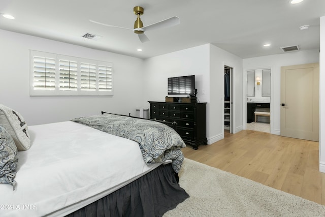 bedroom featuring ceiling fan, connected bathroom, light hardwood / wood-style floors, a spacious closet, and a closet