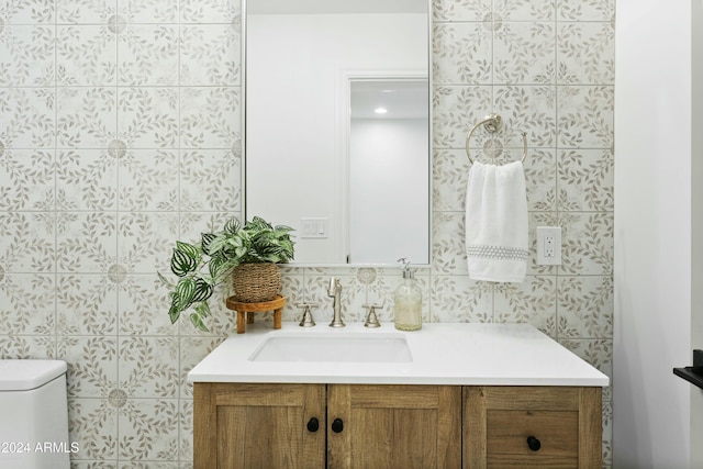 bathroom featuring vanity, toilet, and tile walls