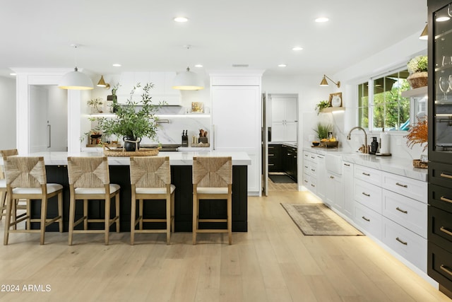 kitchen featuring tasteful backsplash, sink, white cabinets, hanging light fixtures, and a center island