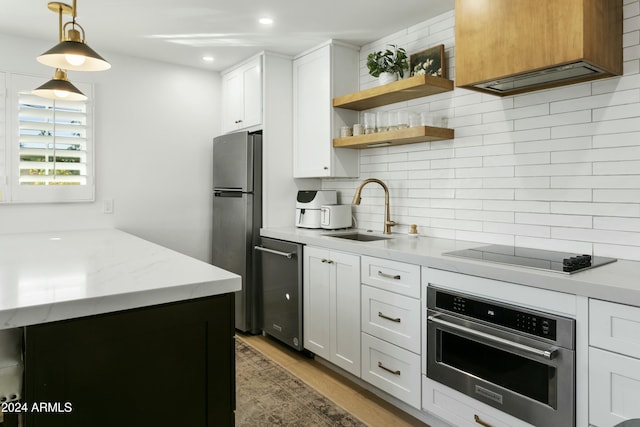 kitchen with white cabinetry, appliances with stainless steel finishes, sink, and light stone counters