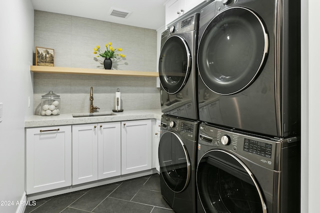 laundry room featuring cabinets, stacked washer and clothes dryer, sink, and dark tile patterned floors