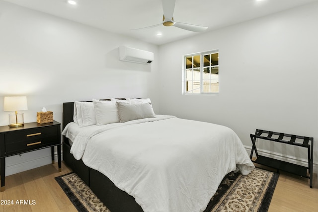 bedroom featuring light wood-type flooring, a wall mounted AC, and ceiling fan