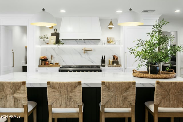 bar featuring pendant lighting, backsplash, range, and premium range hood