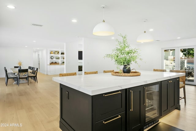 kitchen with wine cooler, a kitchen bar, decorative light fixtures, a center island, and built in features