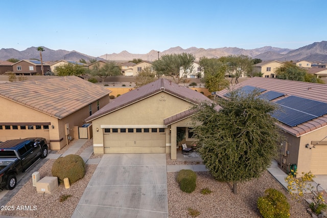 view of front of house with a mountain view, a garage, and solar panels